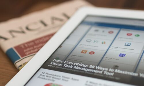 white tablet computer on top of newspaper